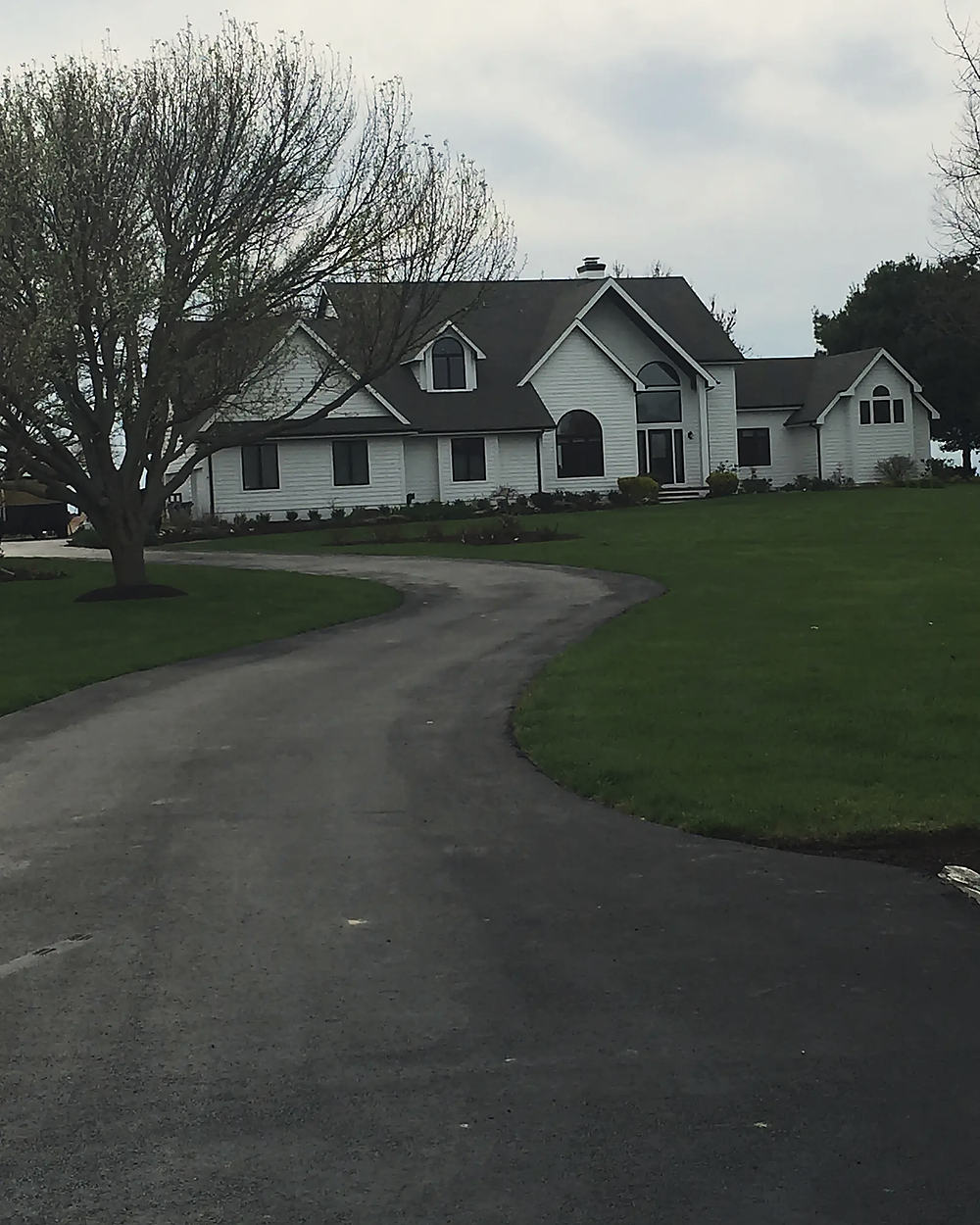 A fresh asphalt S-curve drive up to a country home