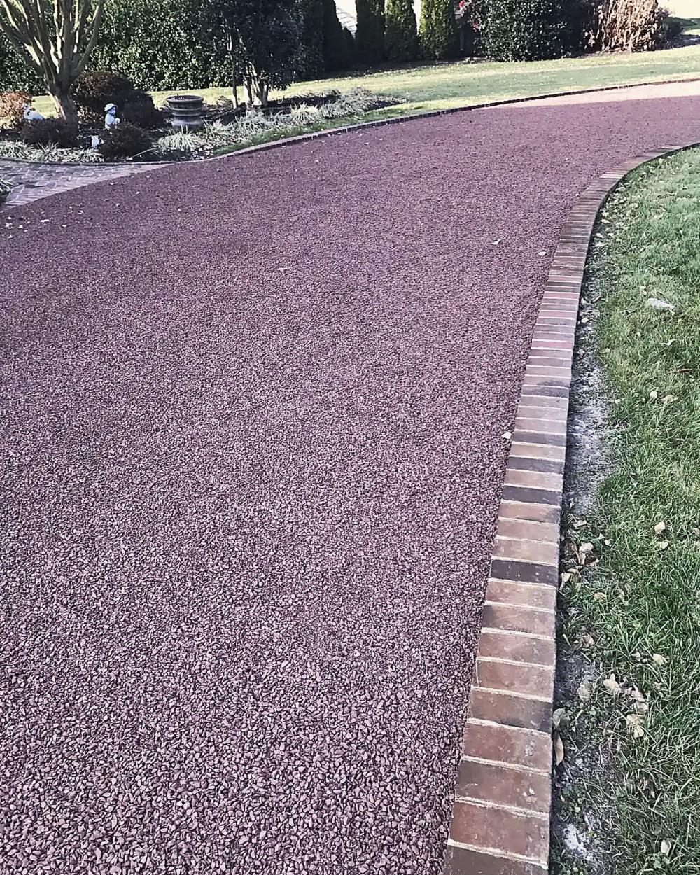 A deep red tar and chip drive with a brick border
