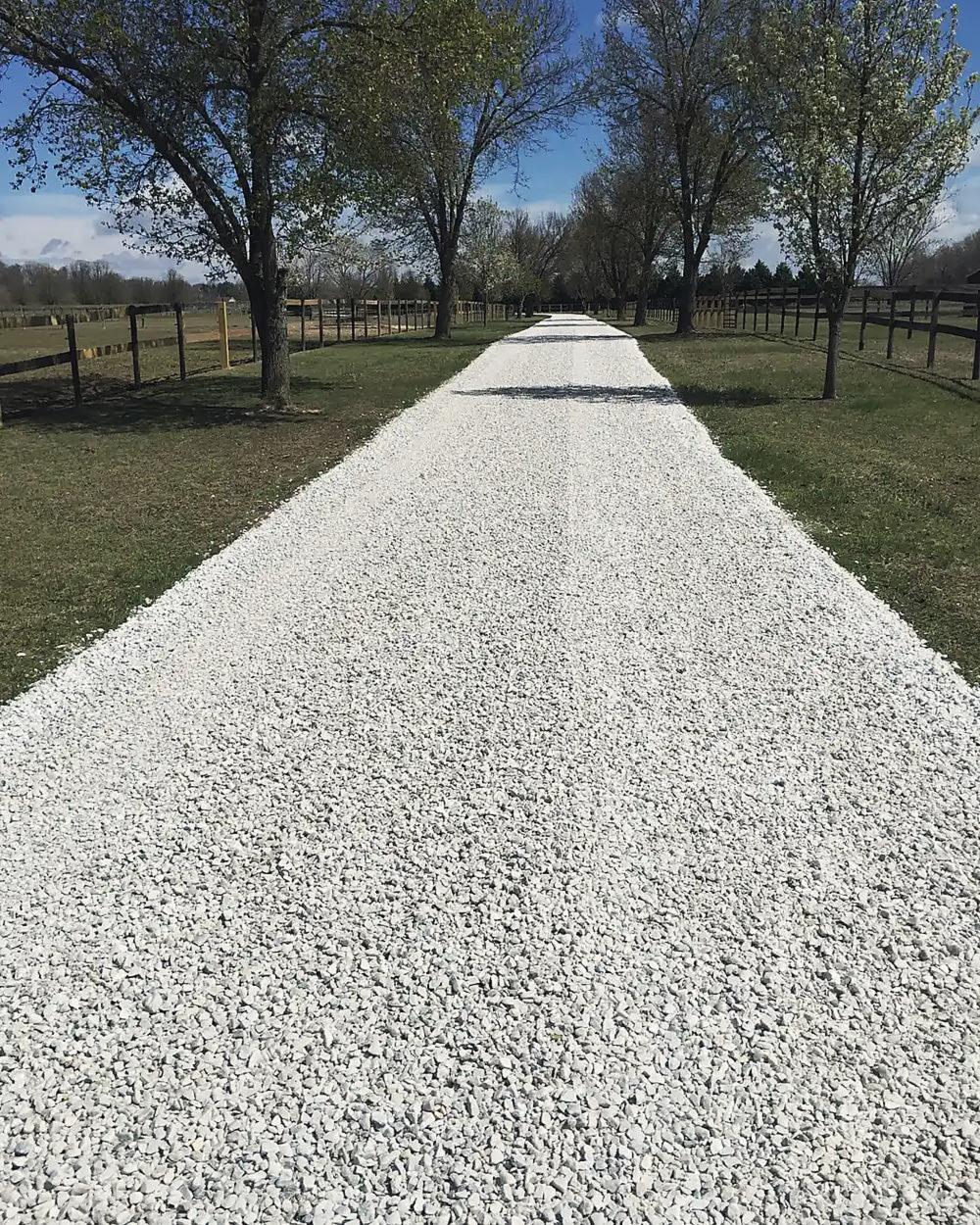 A white stone lane running between horse paddocks